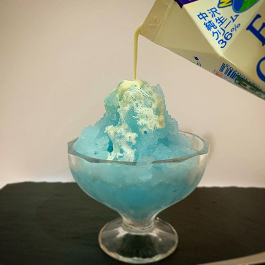 ガリガリ君(赤城乳業)を棒から外してかき氷状にしたものに生クリームをかける様子